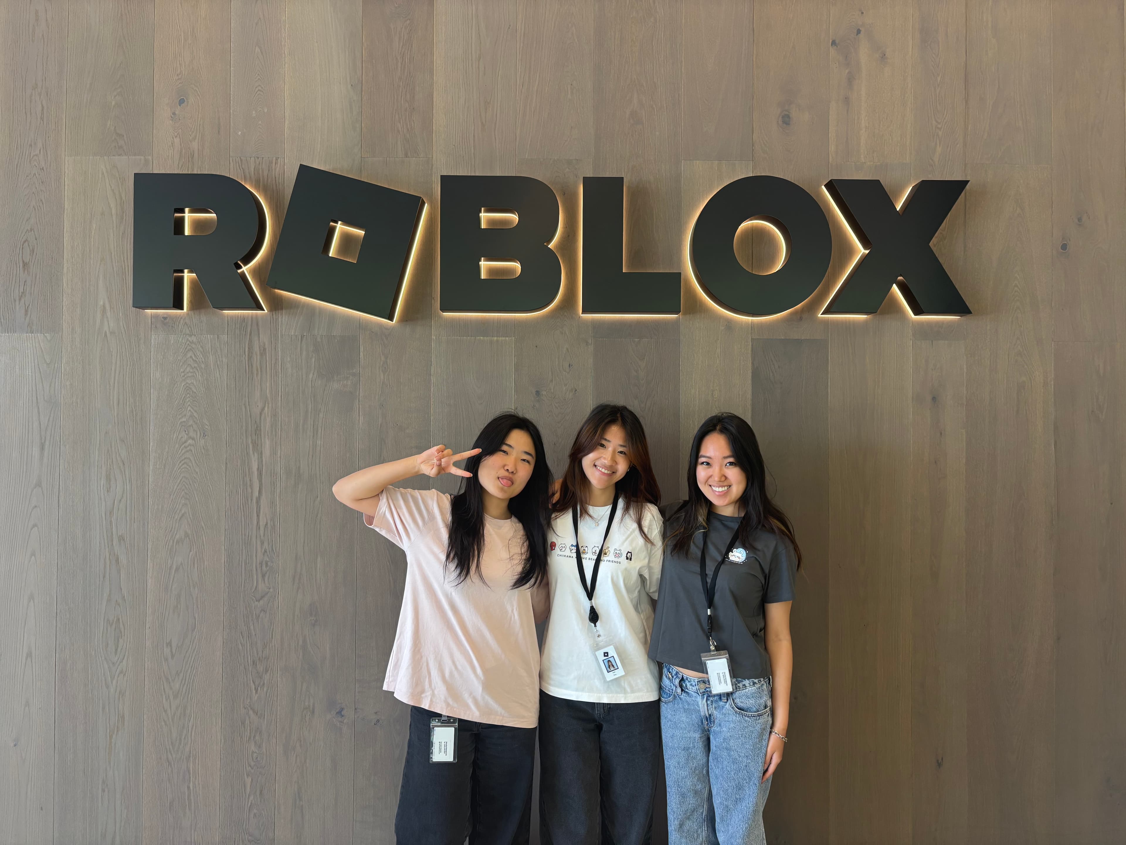 Three interns posing together in front of the Roblox sign.